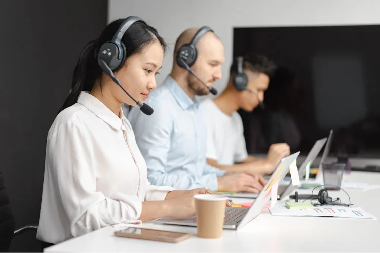A customer service woman wearing a headset typing on a computer