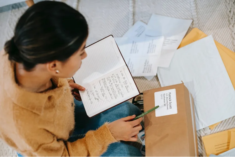 Person with notebook checking address on parcel label