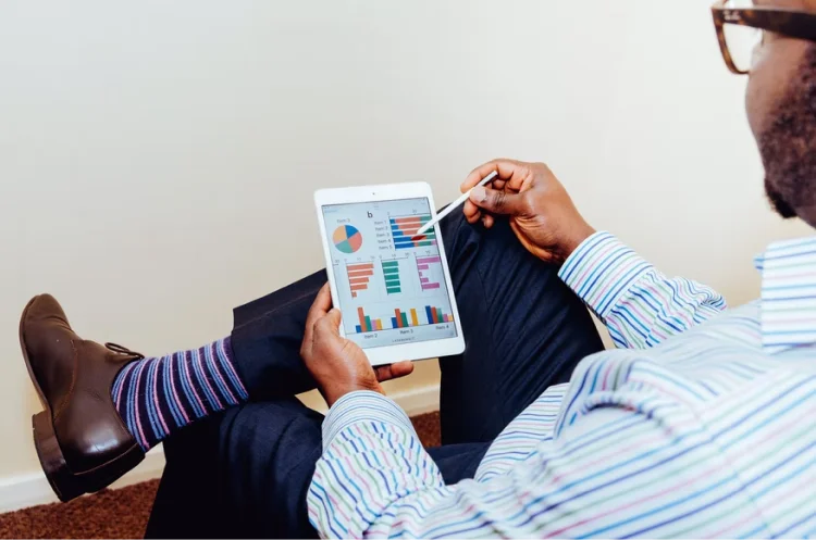 a man uses a stylus on a tablet screen with graphs