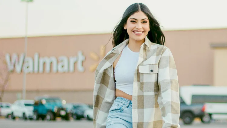 Smiling woman with dark hair in a brown flannel walks away from Walmart super store