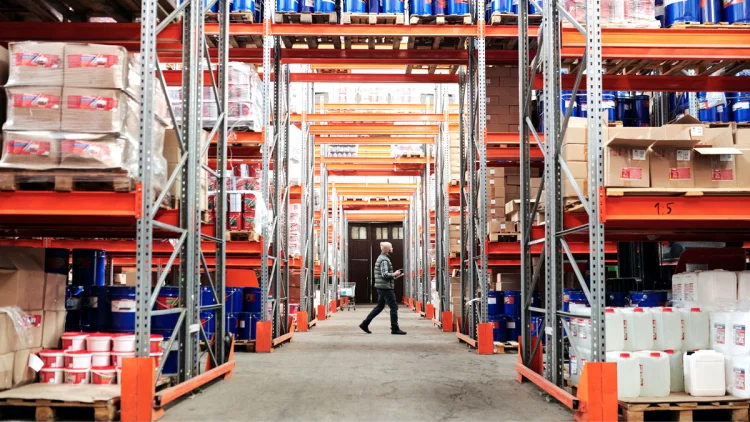 Man walks down the aisle of a big warehouse